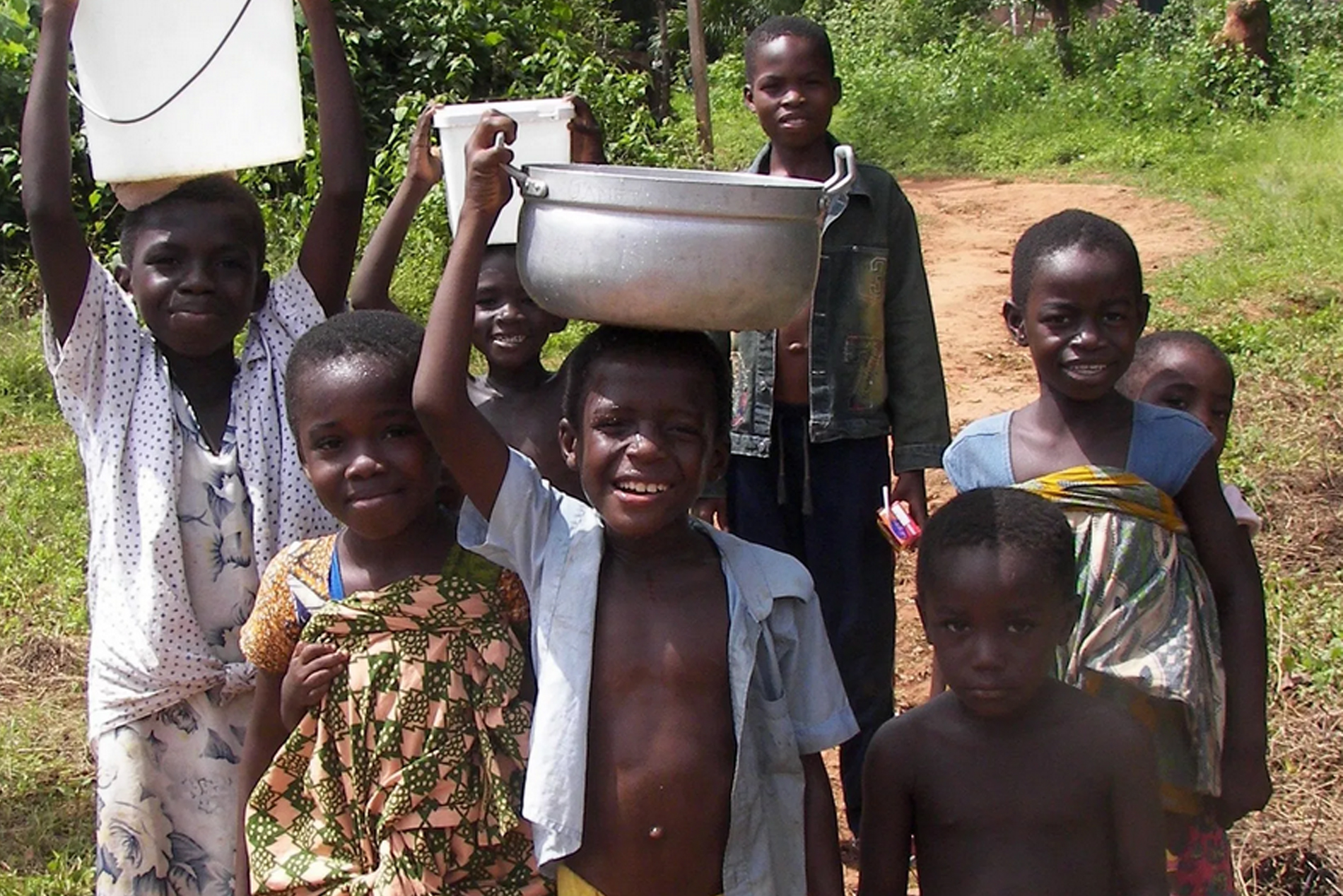 Kinder in Ghana tragen Wasser in Schüsseln und Kanistern